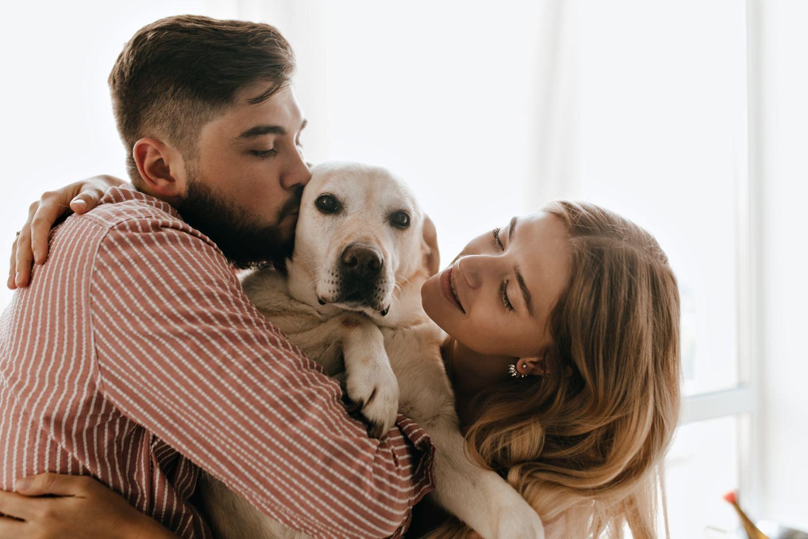 Pareja abrazando a su perro en casa